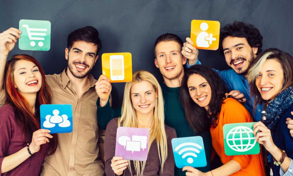 Group of people smiling to camera holding up various internet icons