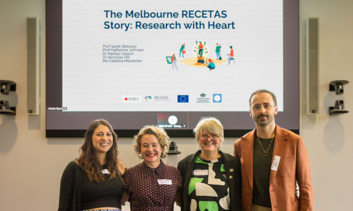 People smiling at the camera in front of presentation.