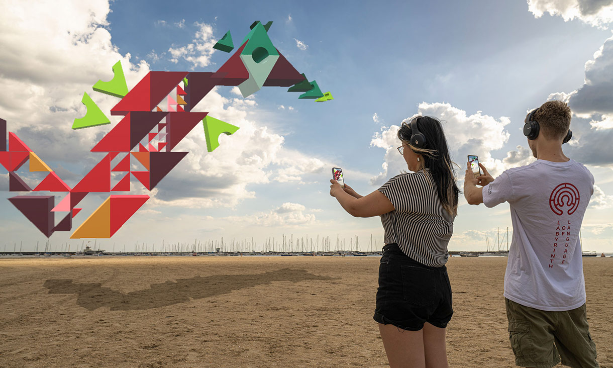 people standing on a beach holding phones and looking at an augmented dragon in the sky