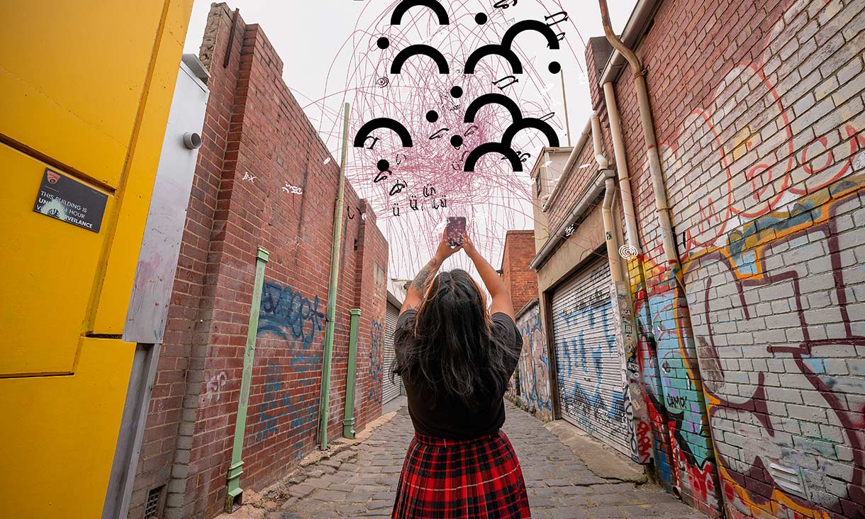 person standing in alleyway holding mobile phone in the air