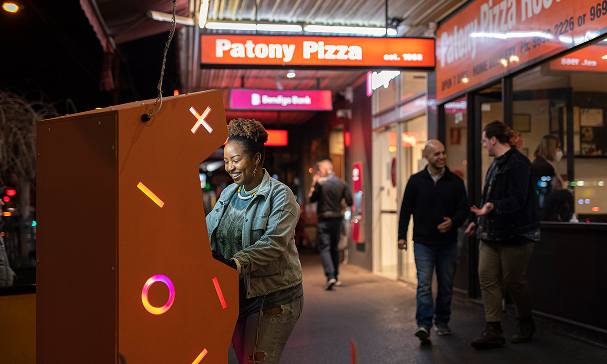 person playing on an arcade set up on the footpath