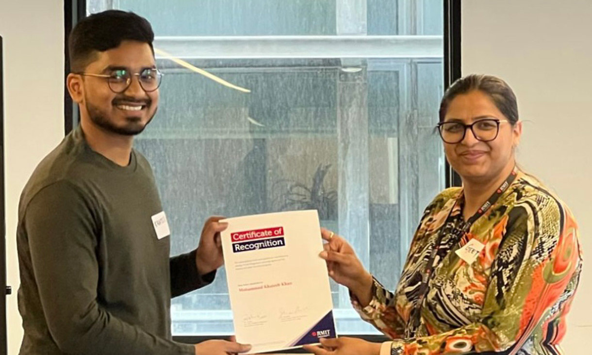 Geetika awarding a certificate to a Masters of Cyber Security student.