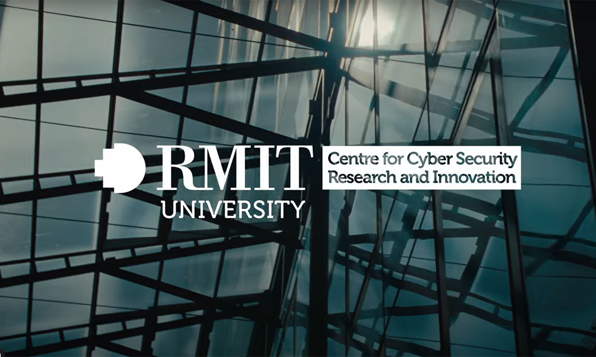 Photograph of the side of a tall building. It's covered in glass windows and has a glass rooftop. The sun reflects off the glass. In the centre is the RMIT University logo and the heading Centre for Cyber Security Research and Innovation.