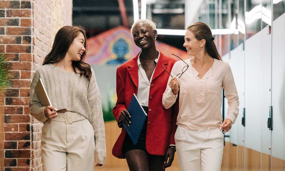 Three women walking down a vibrant corridor laughing