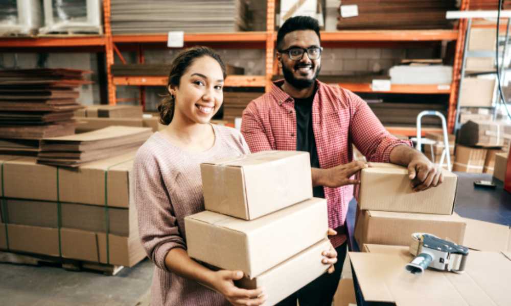 Two people in warehouse of cardboard boxes