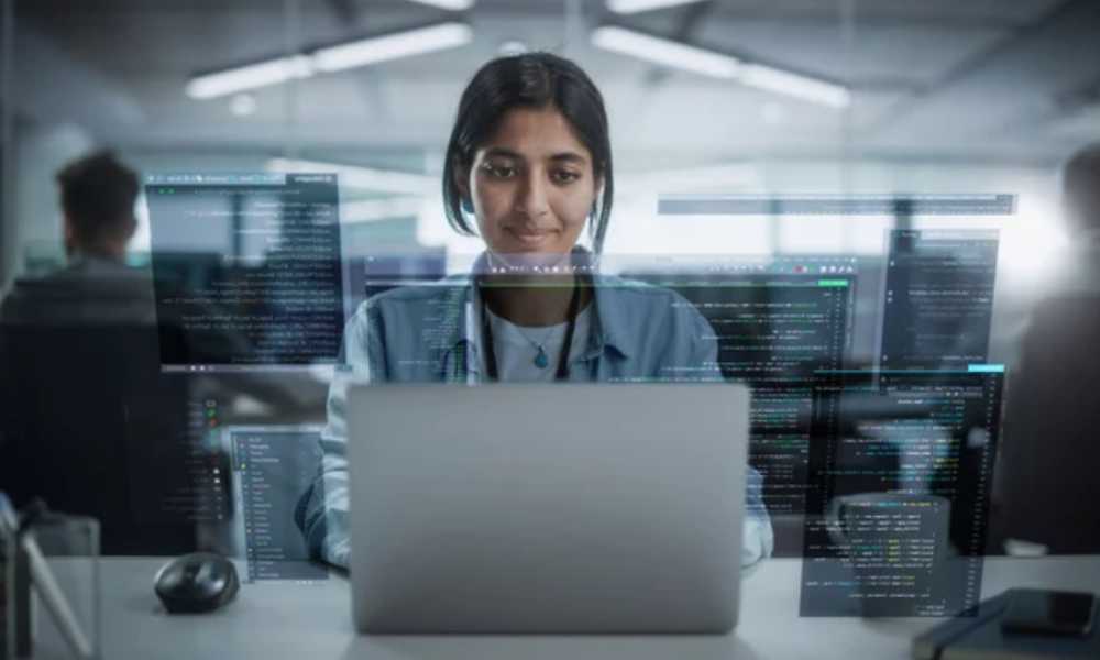 Person using laptop with code holograms around them