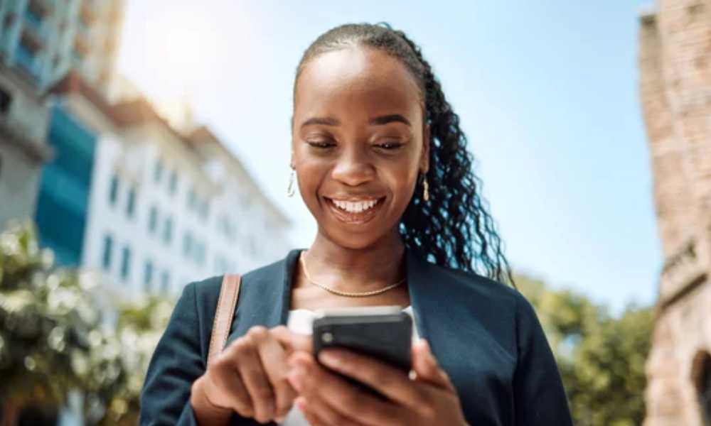 Person smiling and scrolling on their phone outside