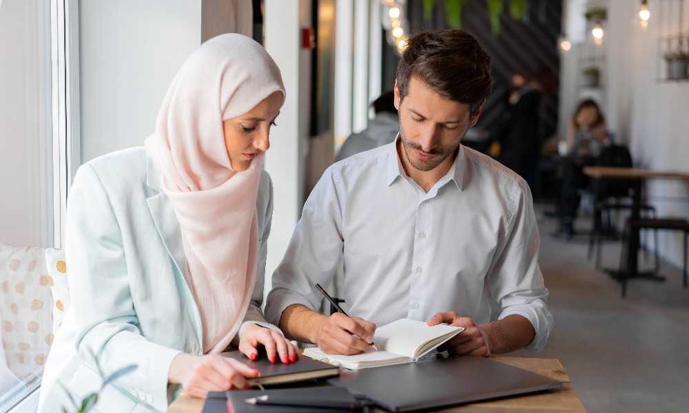 Two business people writing in notebook