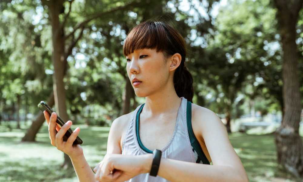 Person wearing activewear wearing a fitness watch and looking at their phone