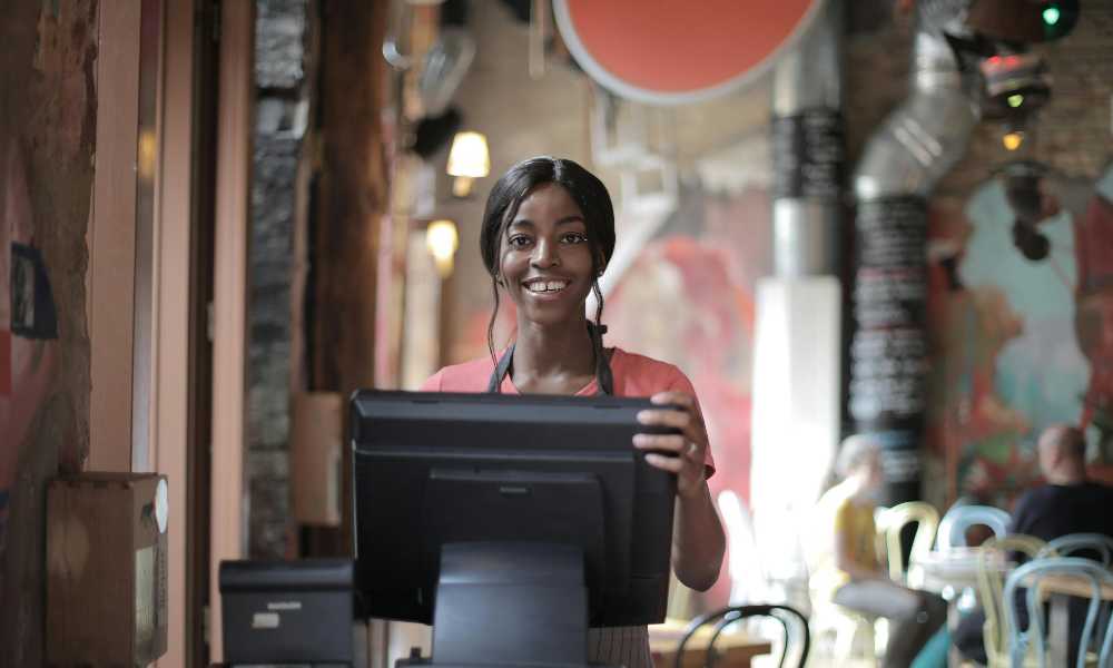Person in front of a monitor smiling to camera in a trendy cafe