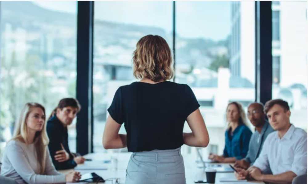 Person standing in front of a conference table with group of people looking towards them