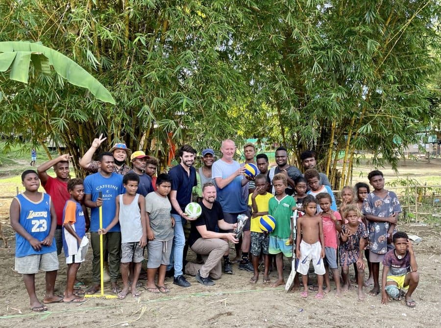 A group of men and children with sporting equipment.
