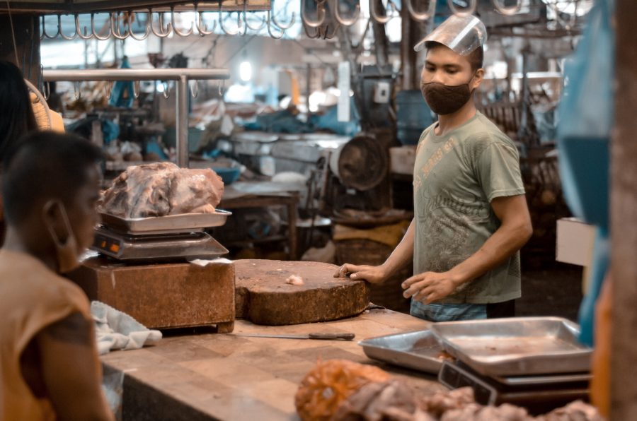 A man in a mask selling meat at a wet market