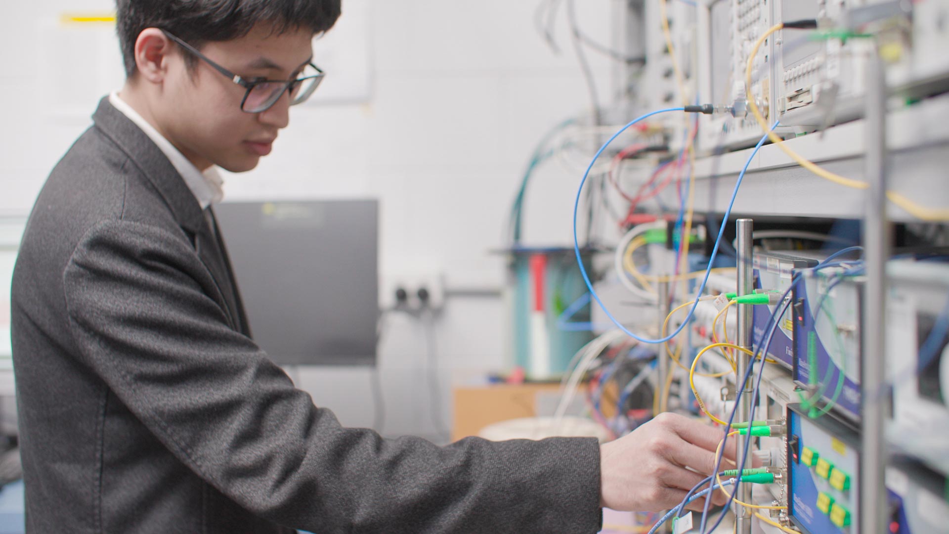A man plugs in a cable to a device covered in coloured wires