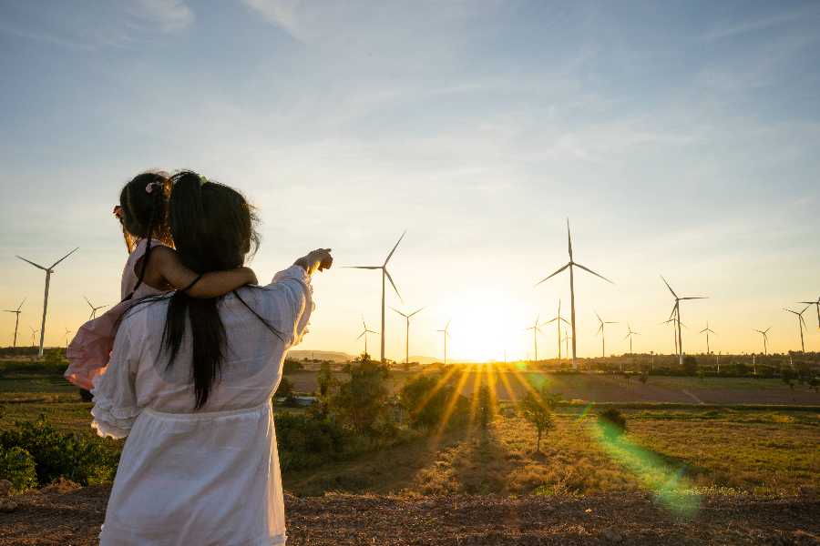 Mother holding small child pointing at windmills in the distance