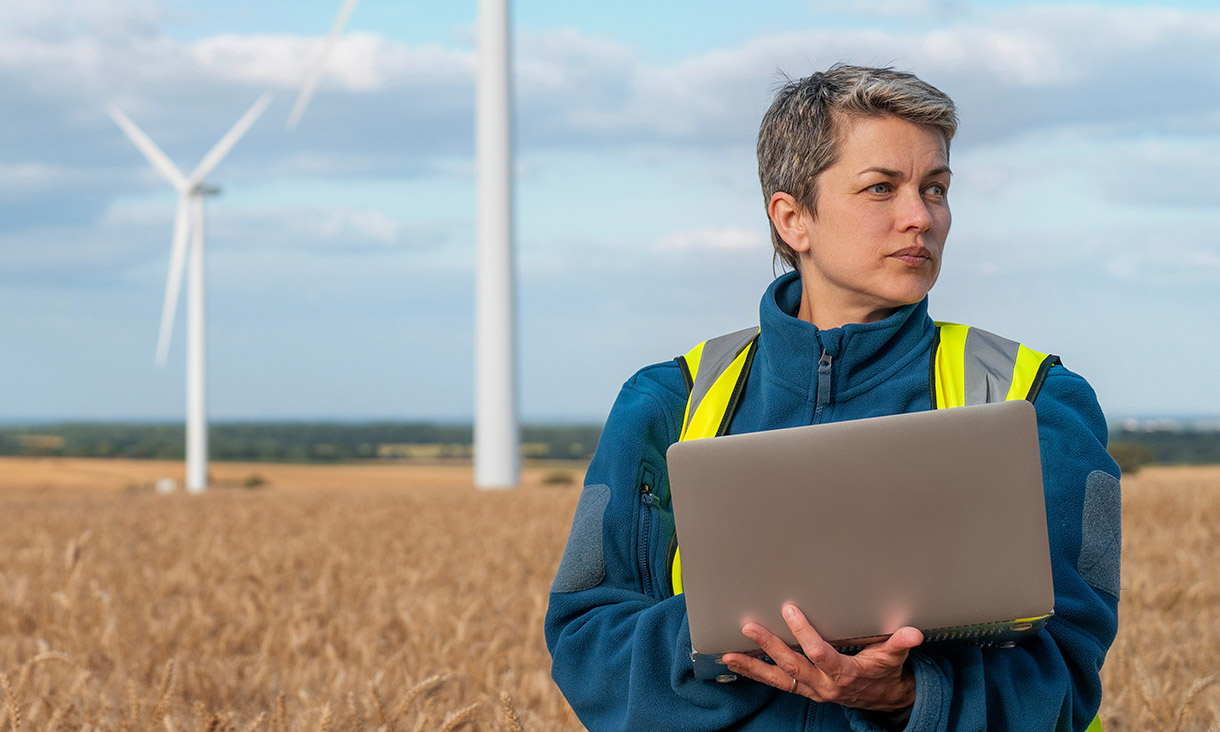 Female wind energy specialist monitors turbine operations in field, showcasing sustainable technology and environmental awareness