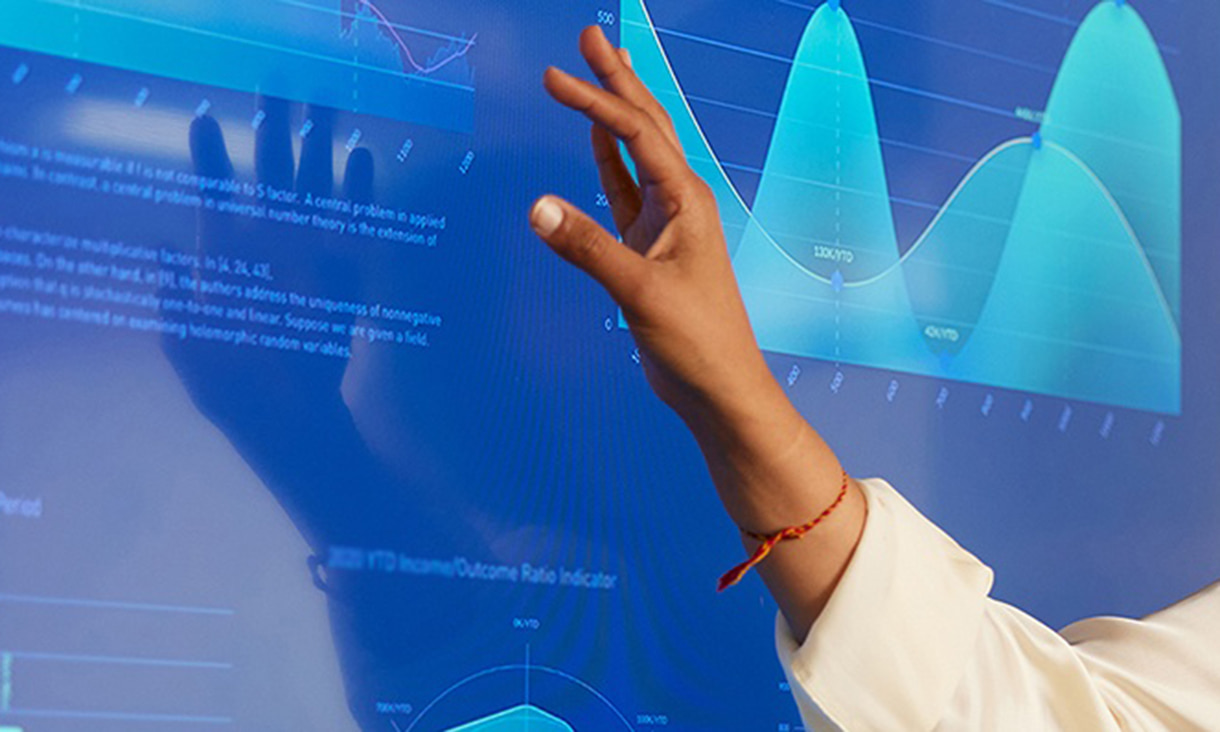 Woman's arm hovering over a display screen showing various data.