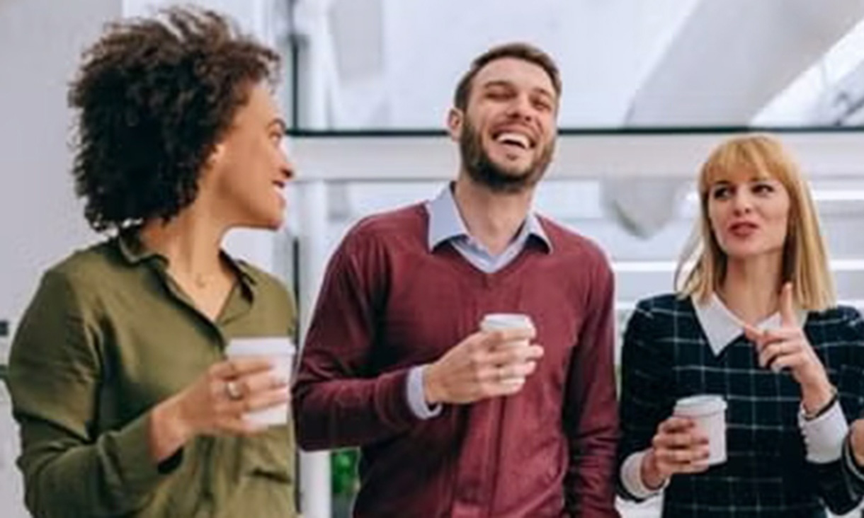 A group of colleagues walking and chatting with coffee together happily.