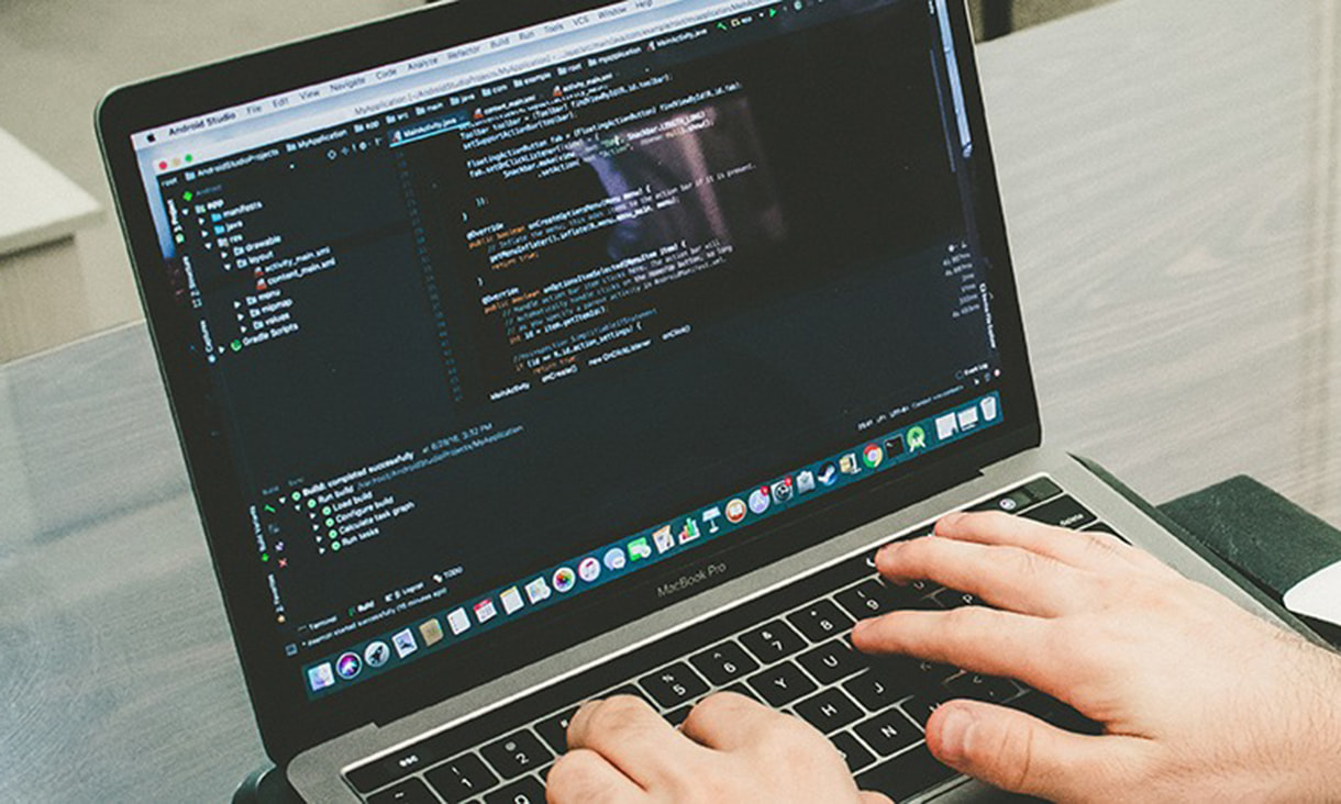 A person works on code on a laptop.
