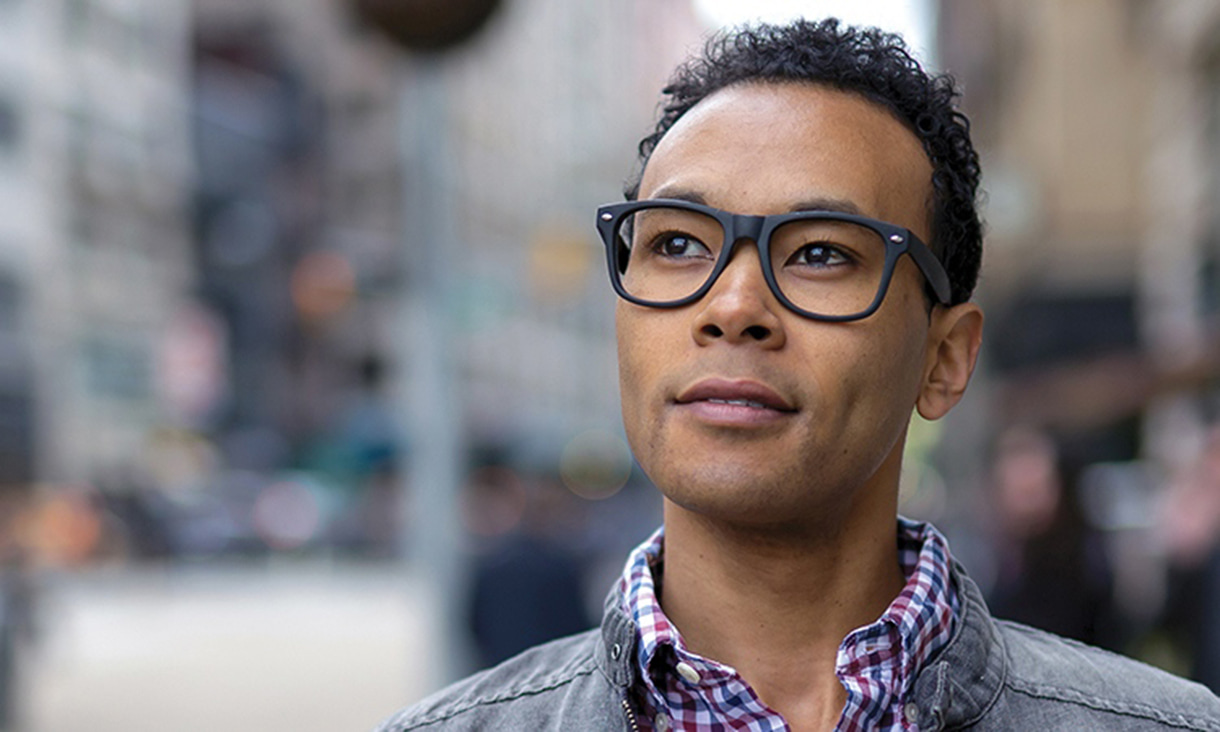 Person wearing glasses with a blurry street behind them.