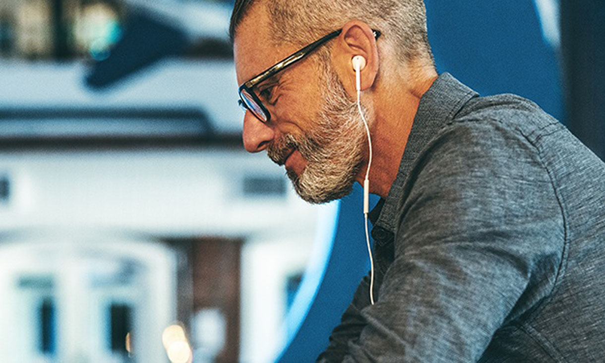 A man on his laptop with headphones plugged in. 