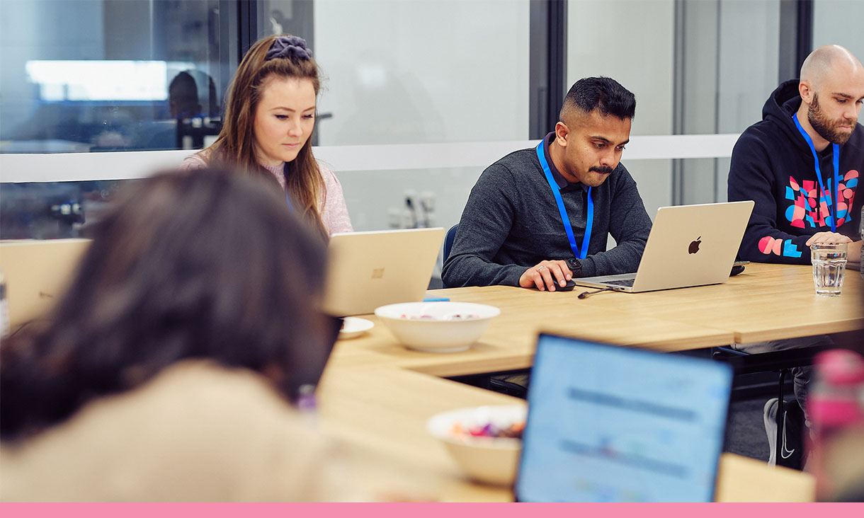 A group of people working at a shared desk.