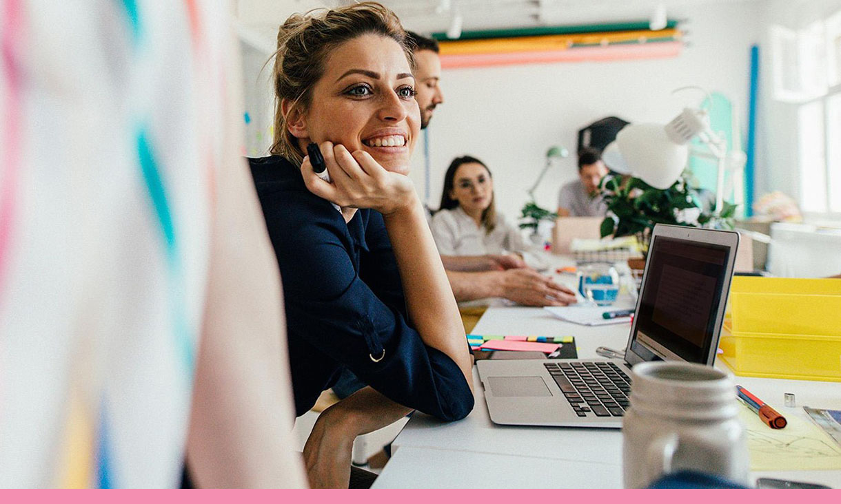 A woman smiles while sitting at her desk.