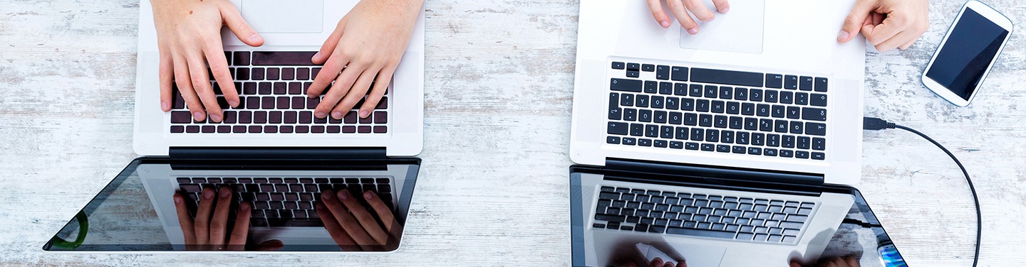 Birds-eye-view of two people using their laptops.
