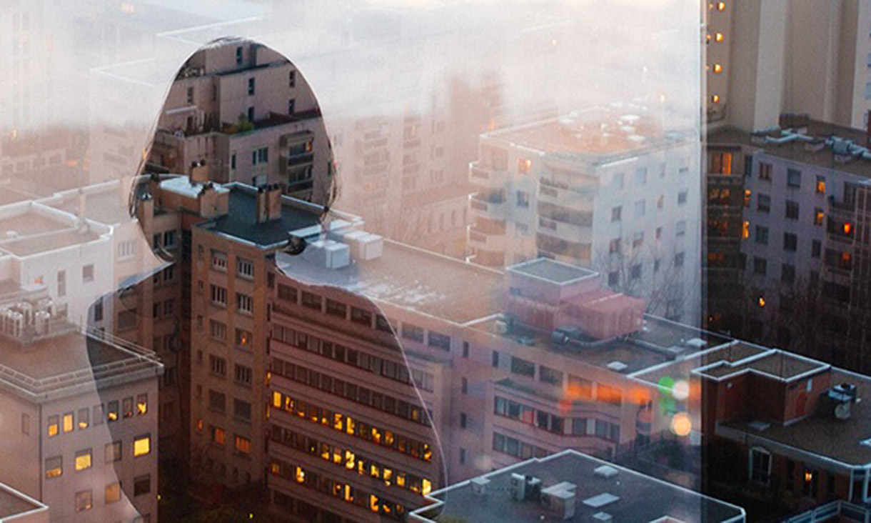 Reflection of a lady from the top floor of a skyscraper overlooking a city.