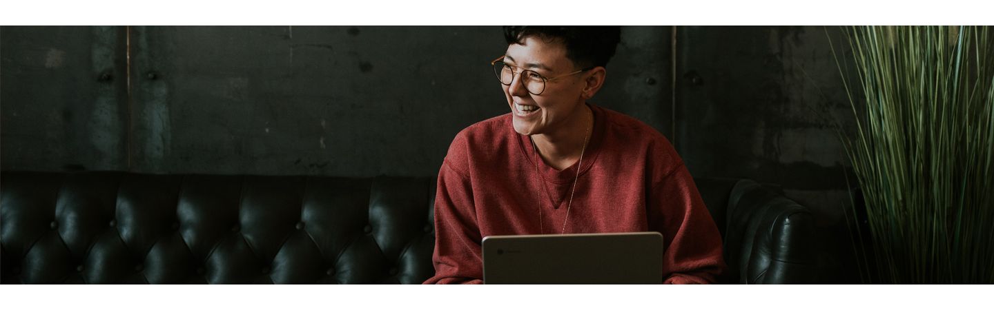 Person sitting, smiling behind a laptop