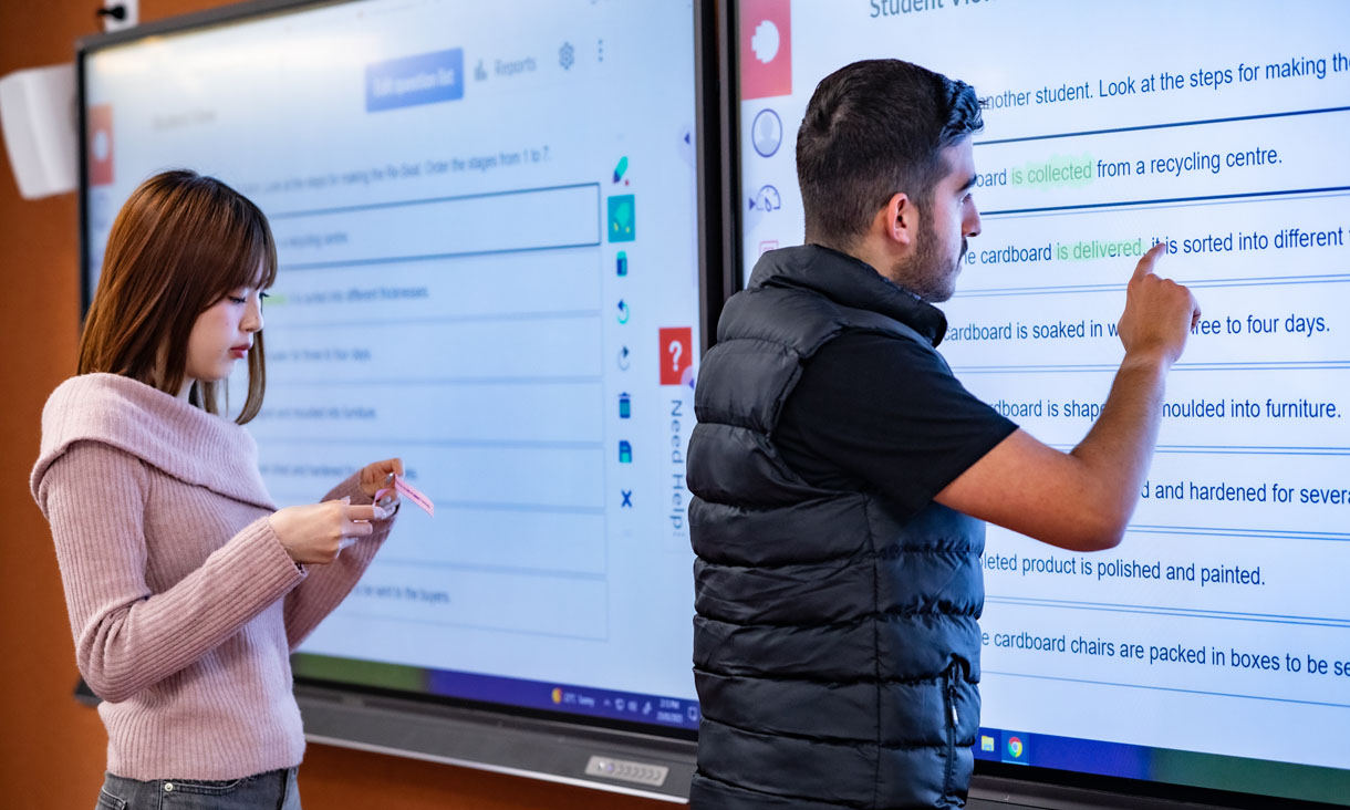 Two international students using an interactive screen in class