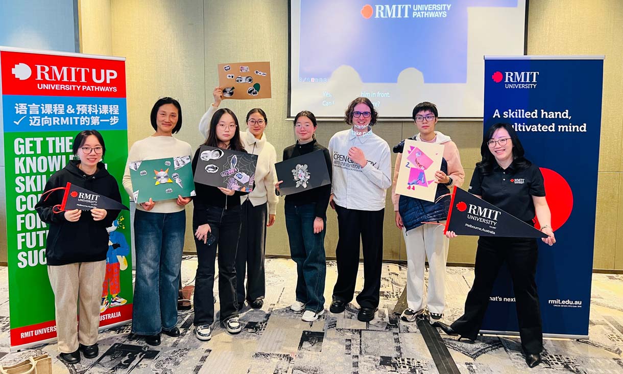 Eight people standing in front of RMIT Banners at Demo class in China