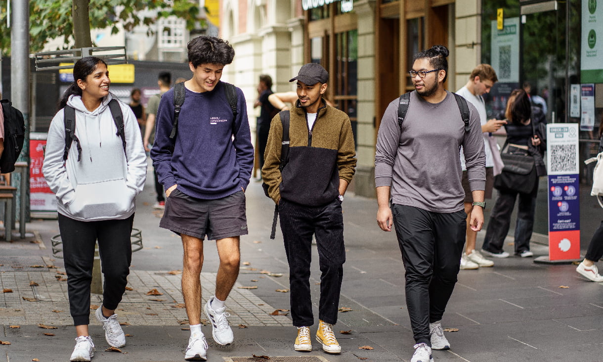 Four students walk on campus talking