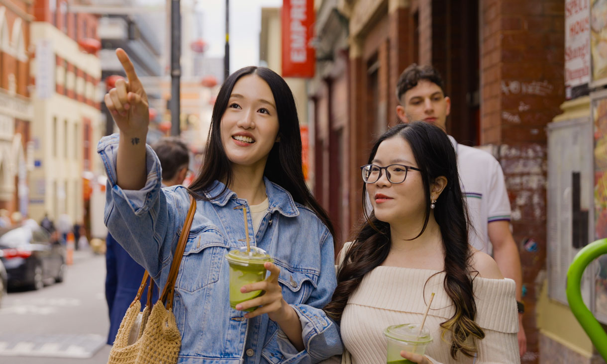 Two students walking down a street drinking matcha
