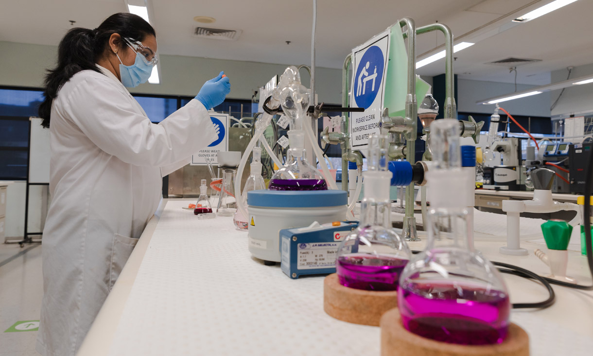 A student working in a science lab full of chemistry equipment