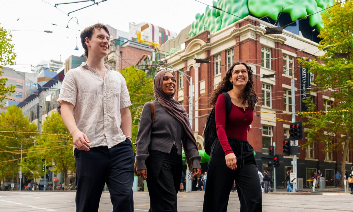 Three RMIT students walking down Swanston Street with Building 22 behind them