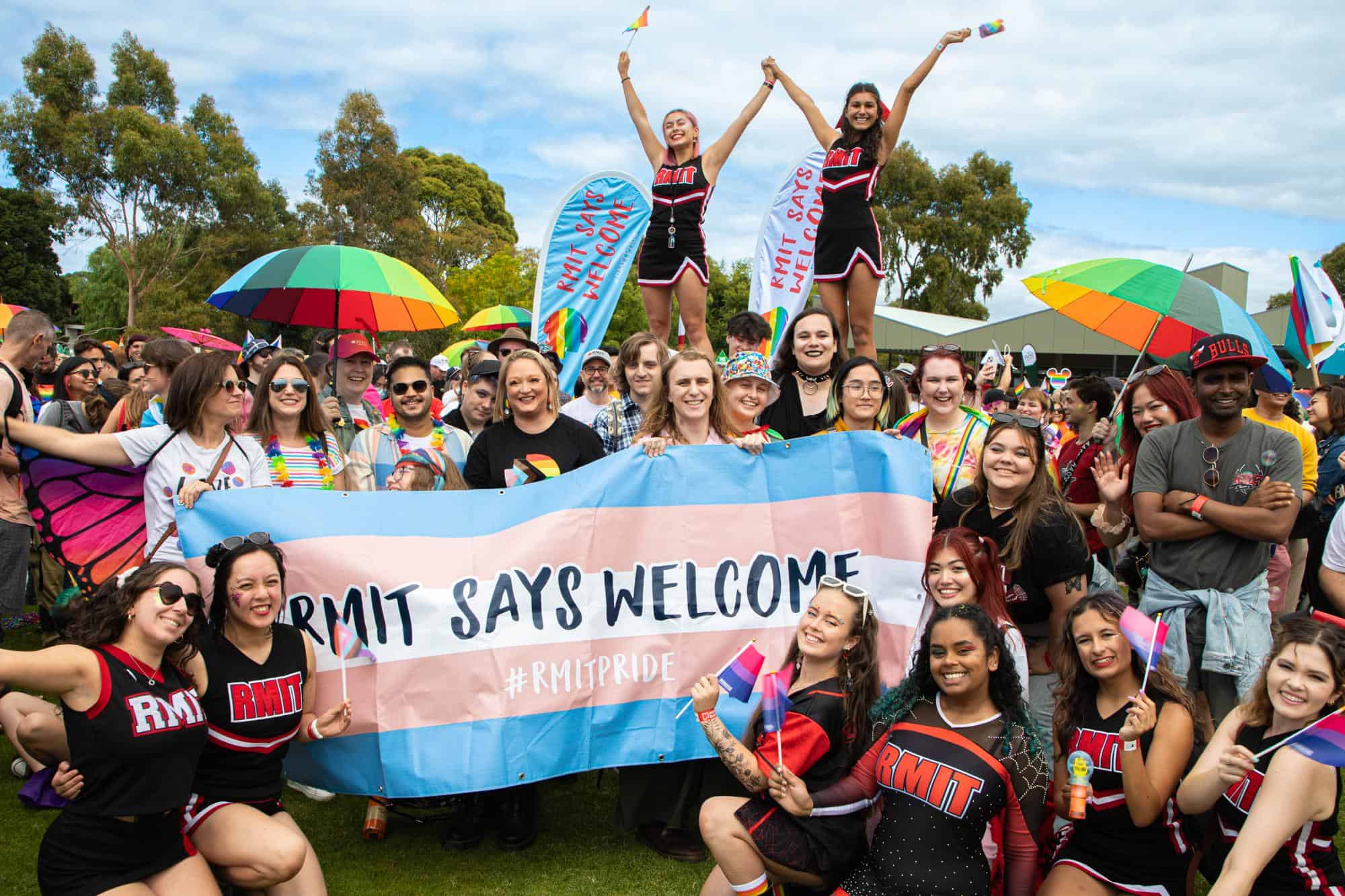 group of people gathered around a trans banner in pink, blue and white