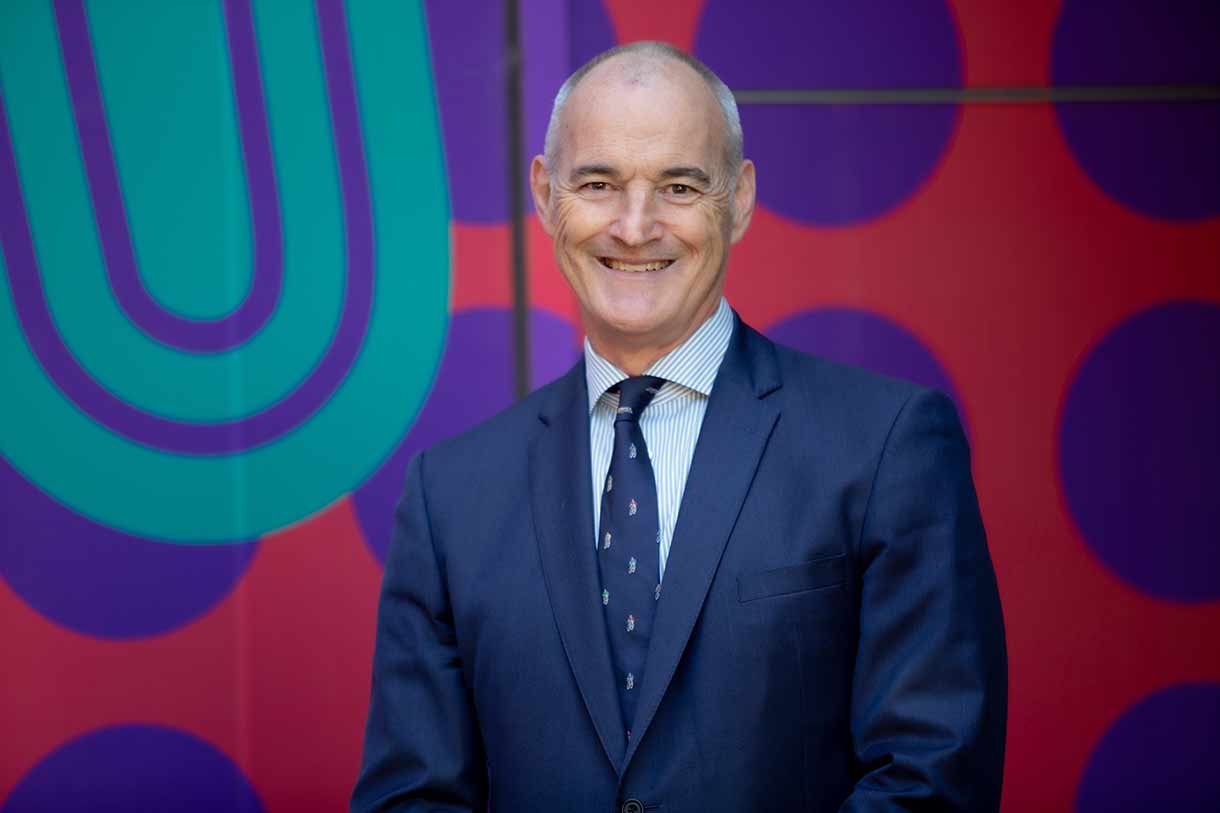 Man standing in front of colour wall smiling at camera