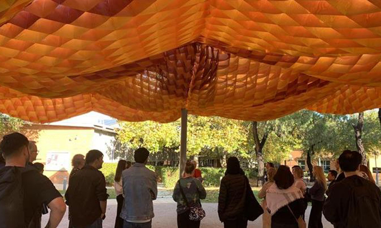 A group of people walking under a colorful fabric canopy.