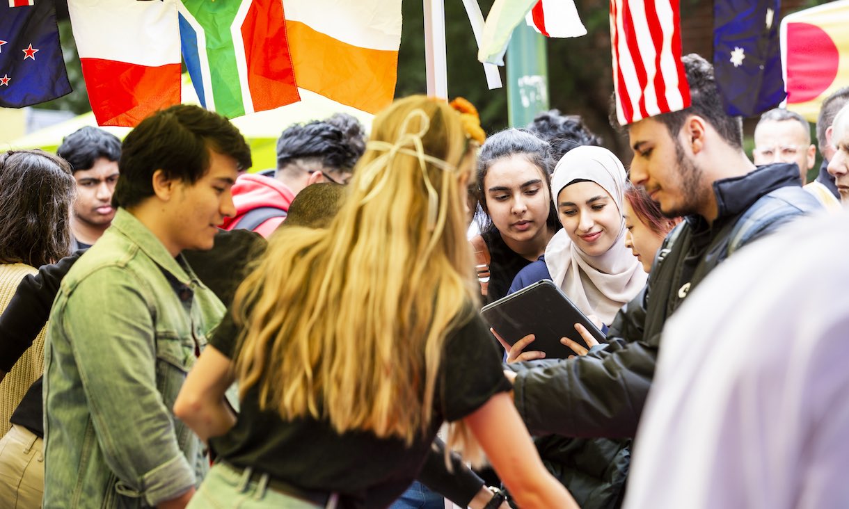 Students look at an iPad at a group event.