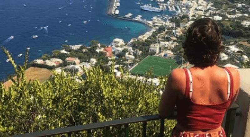 Colleen stands on a mountain looking at a city below.