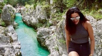 Jessica sits on a rock by a stream.