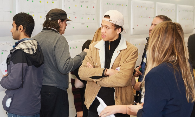A group of students stand talking in a room.