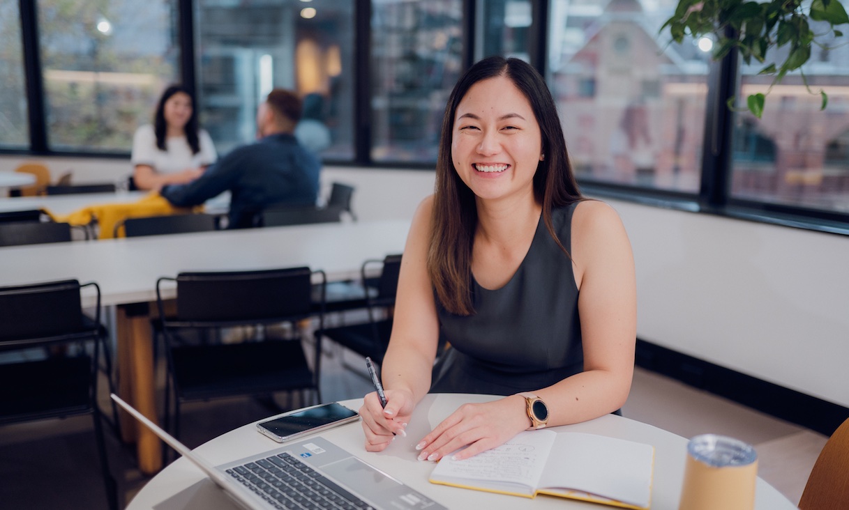 Student with laptop smiling.