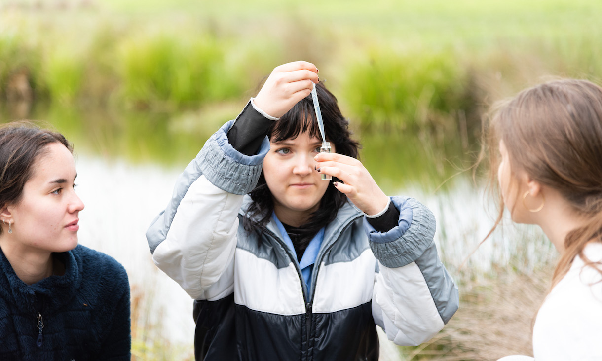 Three students look at a scientific sample.