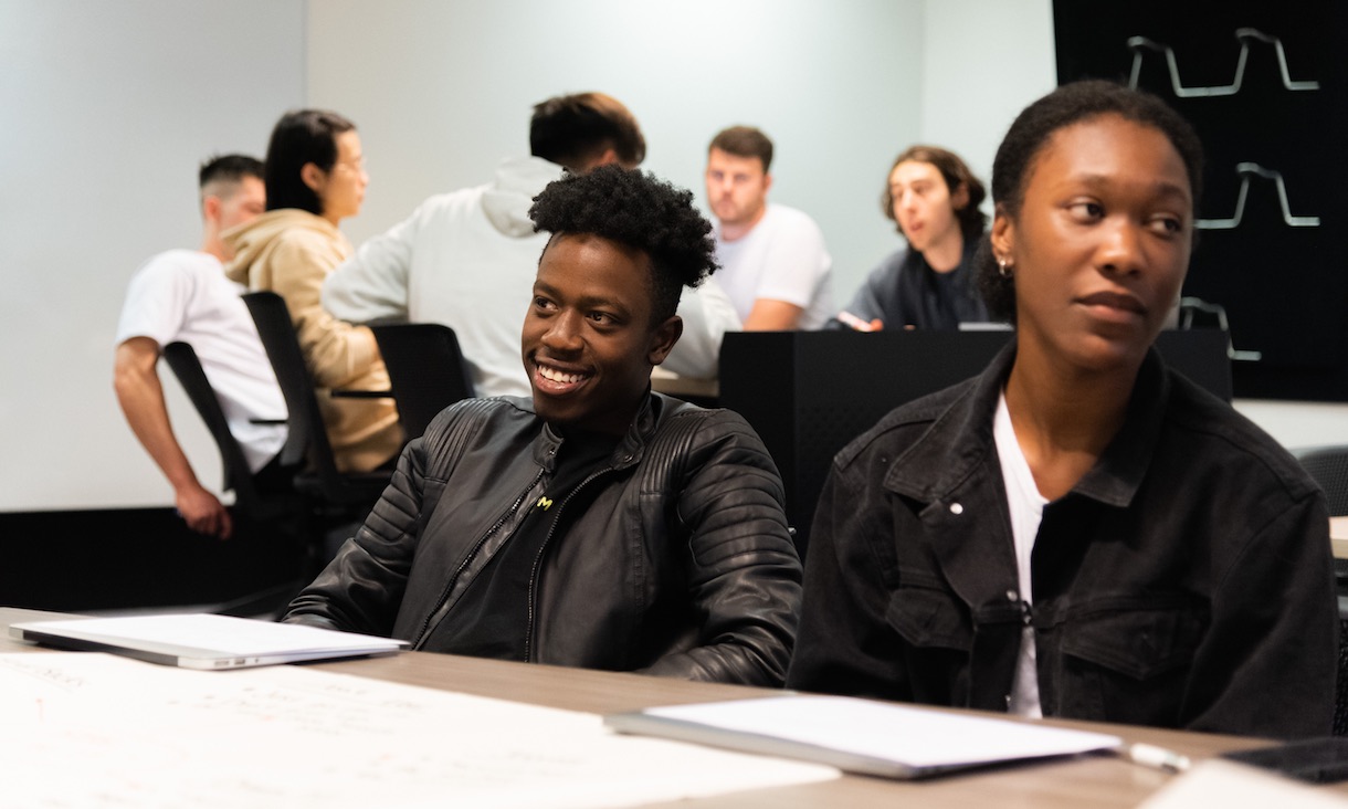 Students have a conversation in a classroom.
