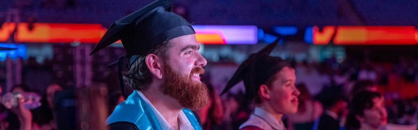 Graduate looks into the distance while smiling at Melbourne Graduation Ceremony.
