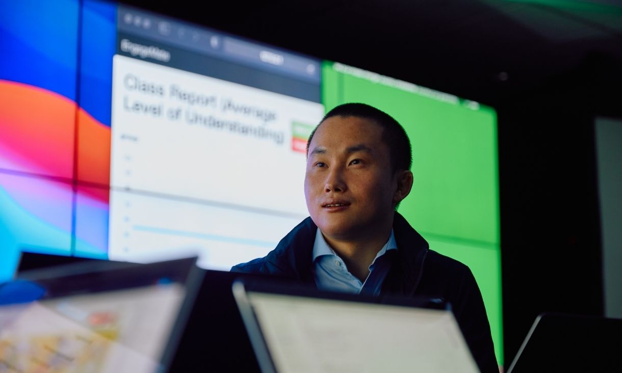 A man stands in front of a digital screen.