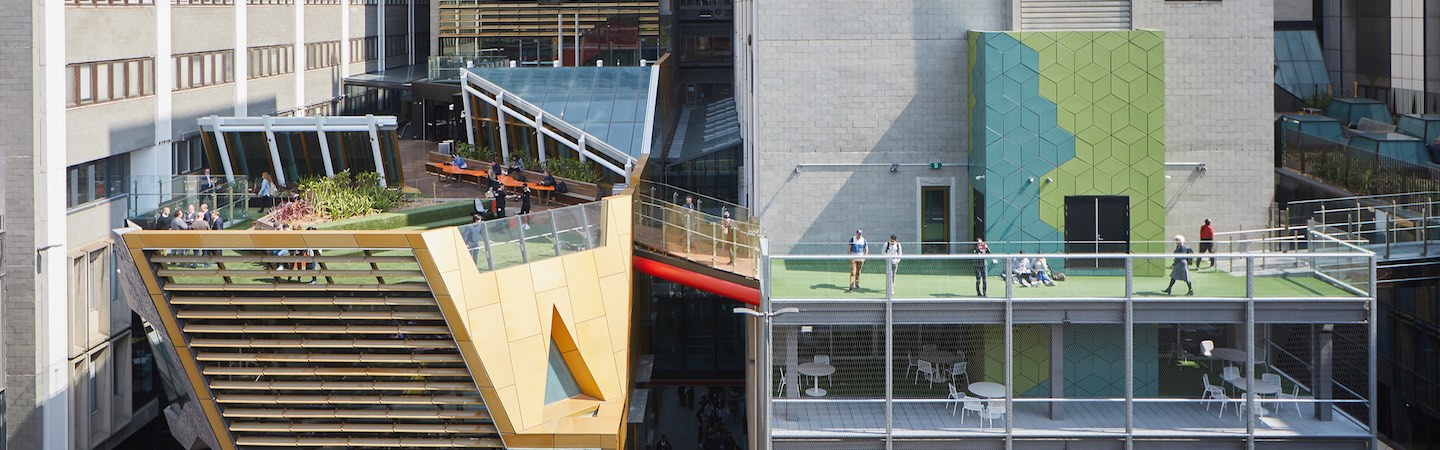 Exterior of a building with balconies and two grassed rooftops connected by a bridge