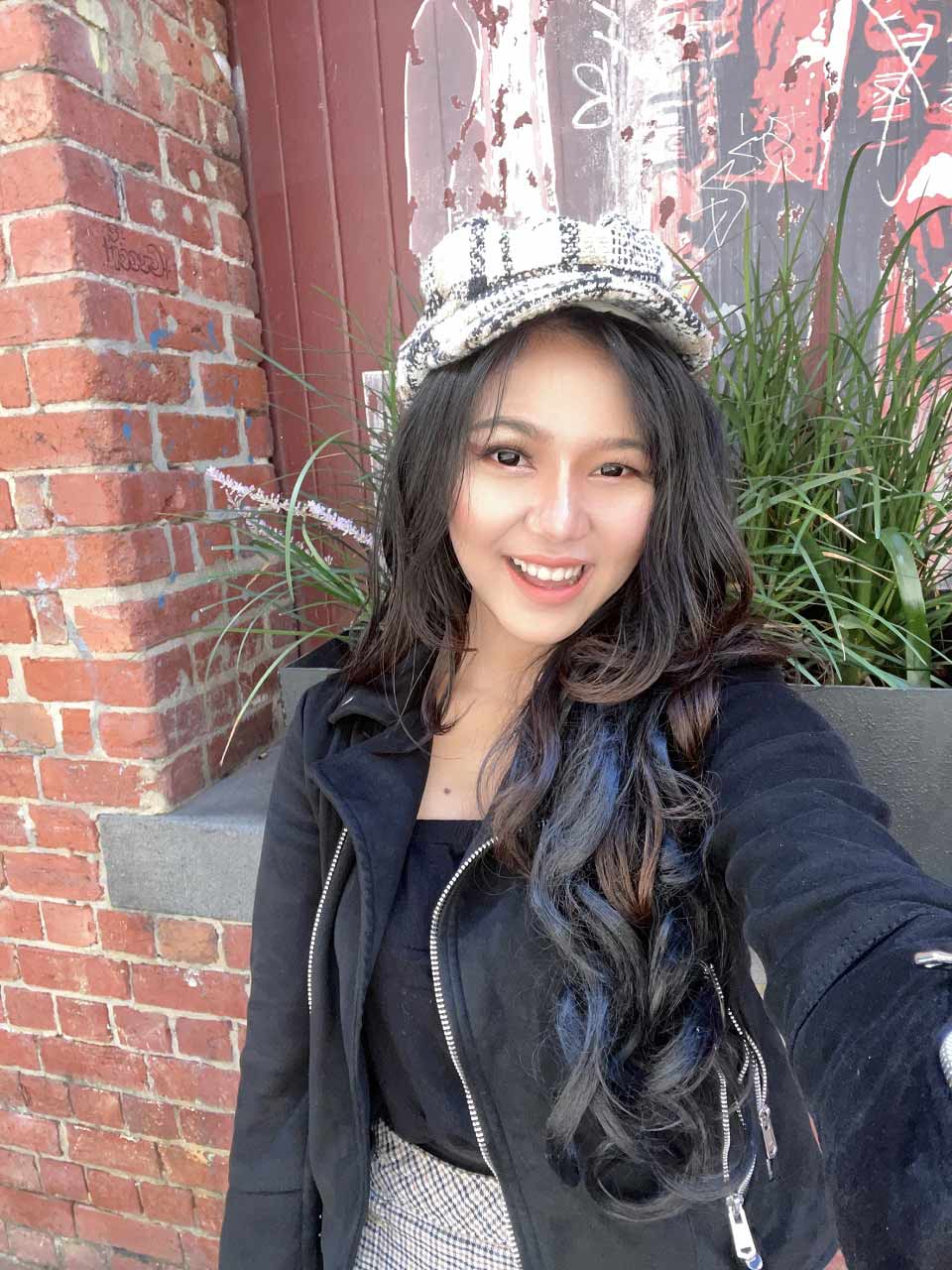 Lara smiling wearing a hat.